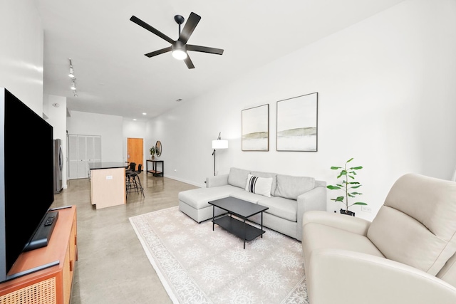 living area featuring ceiling fan, finished concrete floors, and baseboards