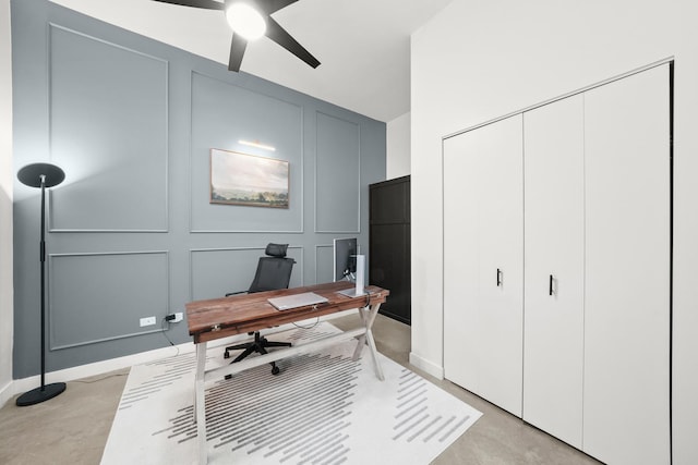 home office featuring ceiling fan, finished concrete floors, and a decorative wall