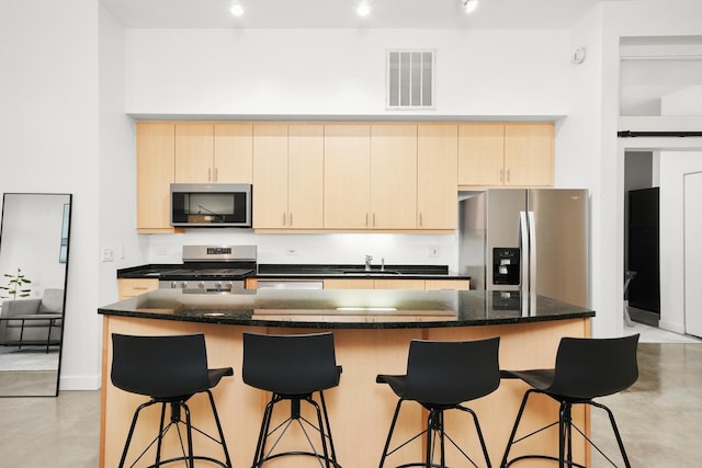 kitchen with visible vents, dark stone counters, a kitchen island, appliances with stainless steel finishes, and concrete flooring