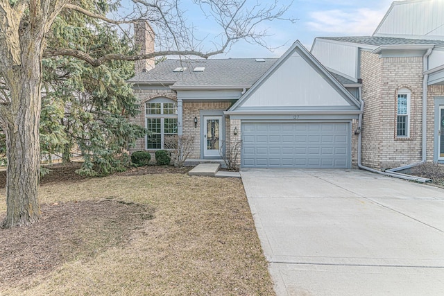 view of front of property with a front lawn, concrete driveway, roof with shingles, a chimney, and a garage