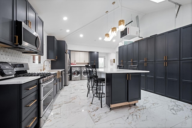 kitchen with stainless steel appliances, lofted ceiling, light countertops, independent washer and dryer, and a kitchen bar