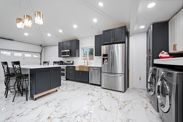 kitchen with tasteful backsplash, washer and clothes dryer, a breakfast bar area, stainless steel appliances, and light countertops