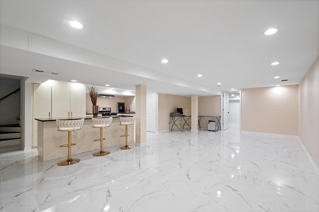 kitchen featuring marble finish floor, recessed lighting, open floor plan, a kitchen breakfast bar, and baseboards