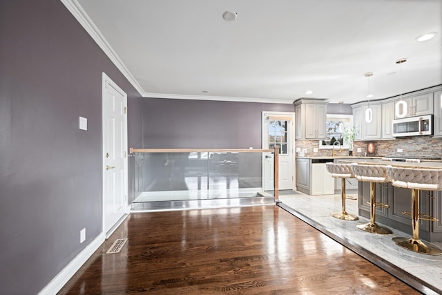 kitchen featuring a breakfast bar, light wood-style floors, baseboards, tasteful backsplash, and crown molding