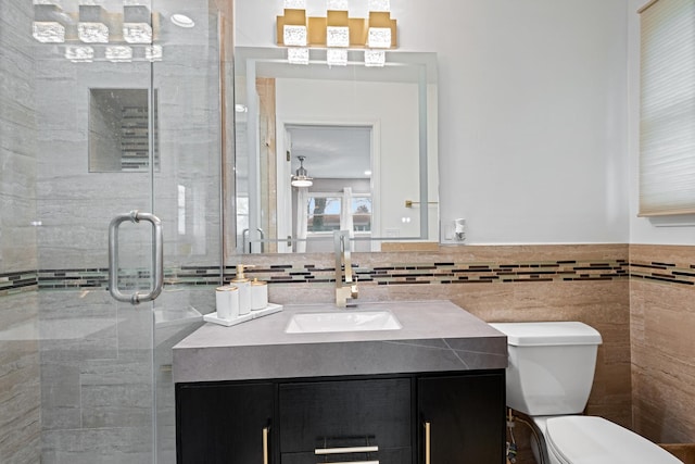 full bathroom featuring toilet, a stall shower, tile walls, and vanity