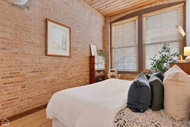 bedroom with brick wall and wood finished floors