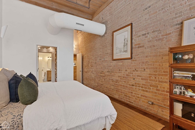 bedroom featuring visible vents, connected bathroom, brick wall, and wood finished floors