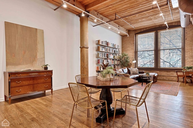 dining room featuring rail lighting, a high ceiling, wood ceiling, wood finished floors, and beamed ceiling