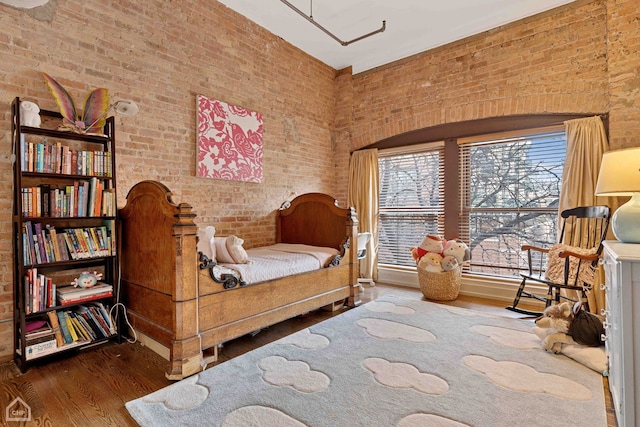 sitting room featuring brick wall and wood finished floors