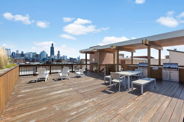 wooden terrace with exterior kitchen, a city view, and area for grilling