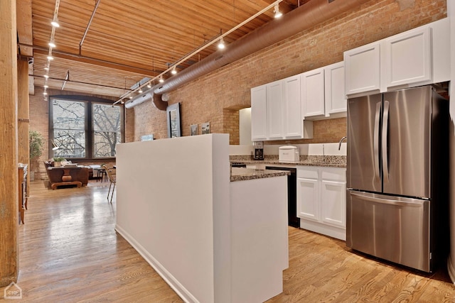 kitchen with light wood-style floors, freestanding refrigerator, and brick wall