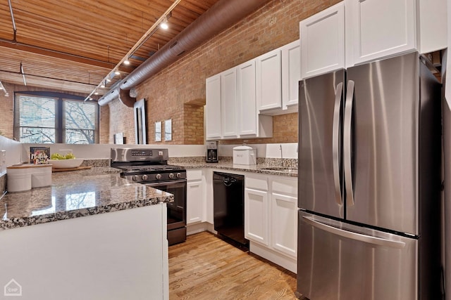 kitchen with brick wall, white cabinetry, stainless steel appliances, and light wood-style flooring