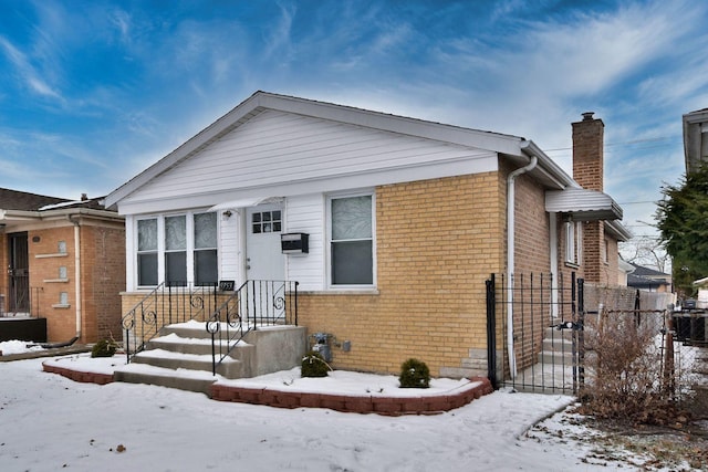 bungalow-style house with a chimney, a gate, fence, and brick siding