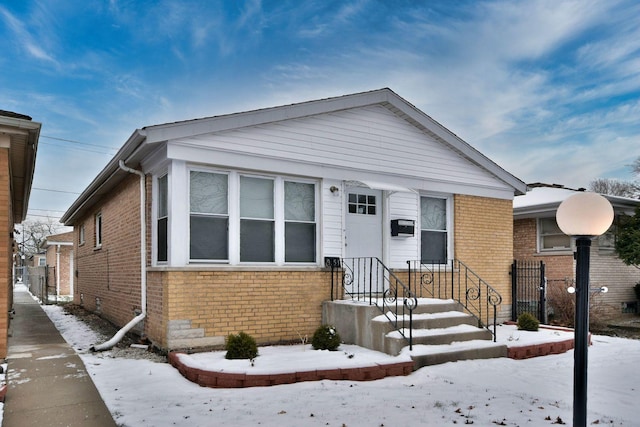 bungalow featuring brick siding