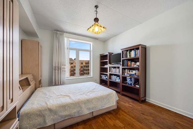 bedroom with a textured ceiling, wood finished floors, and baseboards