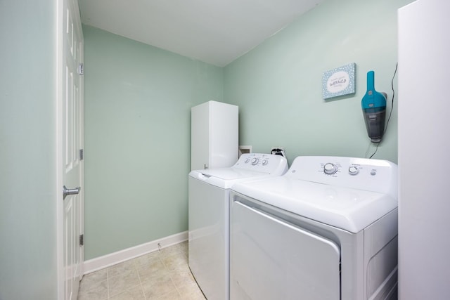 washroom with light tile patterned floors, laundry area, washer and clothes dryer, and baseboards