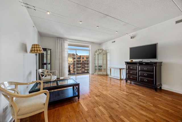 sitting room with a textured ceiling, wood finished floors, visible vents, and rail lighting