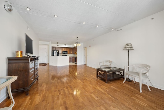 sitting room featuring a textured ceiling, baseboards, and wood finished floors