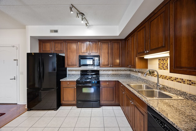 kitchen with light tile patterned floors, tasteful backsplash, visible vents, black appliances, and a sink