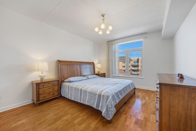 bedroom featuring an inviting chandelier, baseboards, and wood finished floors