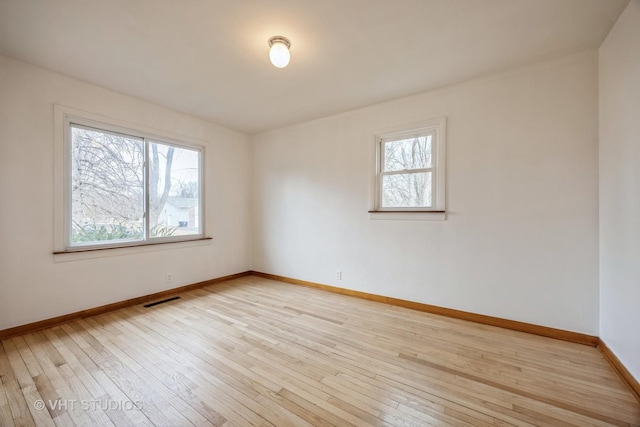 unfurnished room with light wood-style floors, visible vents, and baseboards