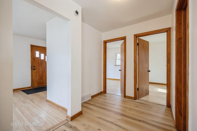 hall featuring baseboards, visible vents, and light wood-style floors