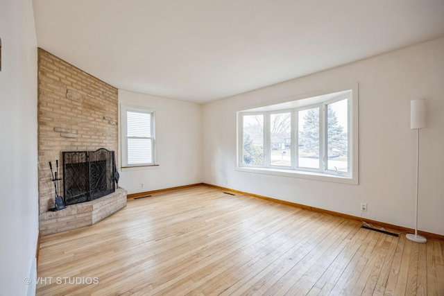 unfurnished living room featuring wood-type flooring, a fireplace, visible vents, and baseboards