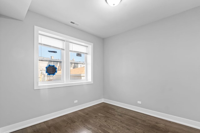 unfurnished room featuring dark wood-style floors, visible vents, and baseboards