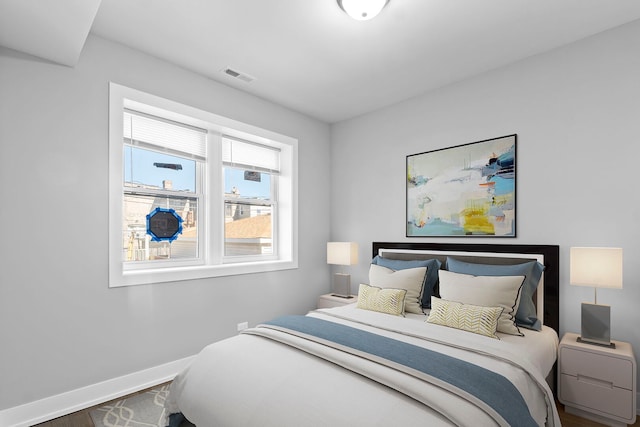 bedroom featuring visible vents, baseboards, and wood finished floors