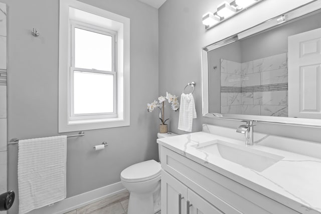 bathroom featuring vanity, a tile shower, toilet, and baseboards