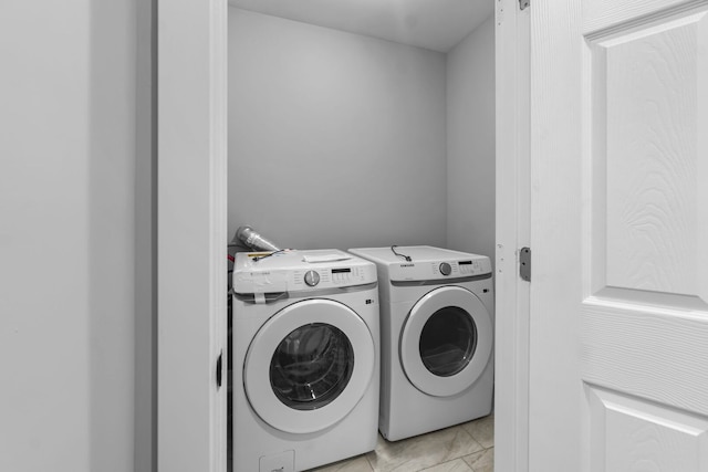 washroom featuring laundry area, light tile patterned floors, and washing machine and clothes dryer