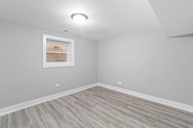 spare room featuring light wood-type flooring, baseboards, and visible vents