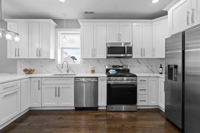 kitchen with visible vents, appliances with stainless steel finishes, decorative light fixtures, white cabinetry, and a sink