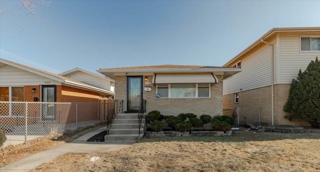 view of front of home featuring entry steps, brick siding, and fence