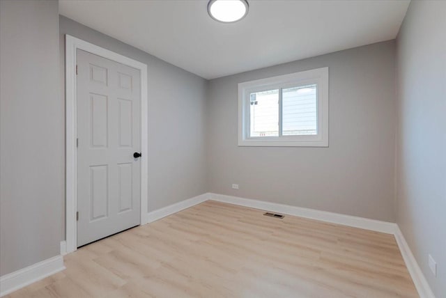 spare room with visible vents, light wood finished floors, and baseboards