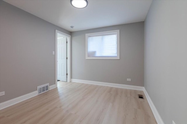 empty room featuring light wood-style flooring, visible vents, and baseboards