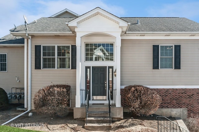 property entrance featuring brick siding and roof with shingles