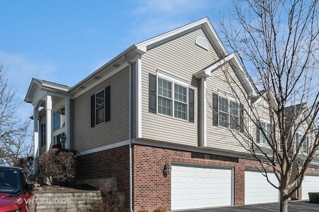 view of home's exterior with brick siding, an attached garage, and aphalt driveway