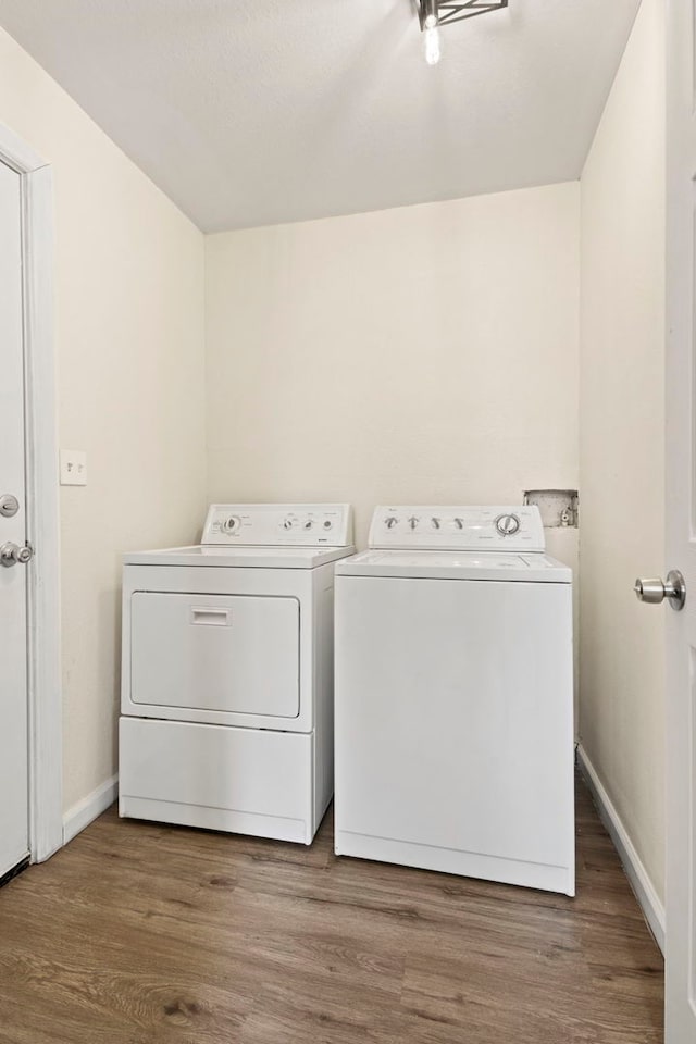 laundry room featuring laundry area, wood finished floors, washing machine and dryer, and baseboards