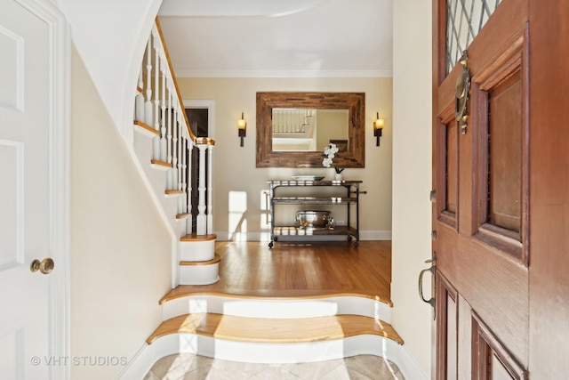 entryway featuring ornamental molding, stairway, and baseboards