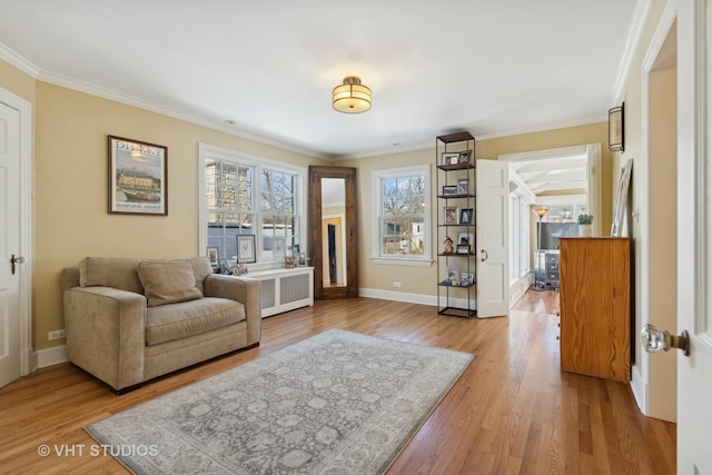 living area with light wood-type flooring, baseboards, crown molding, and radiator heating unit