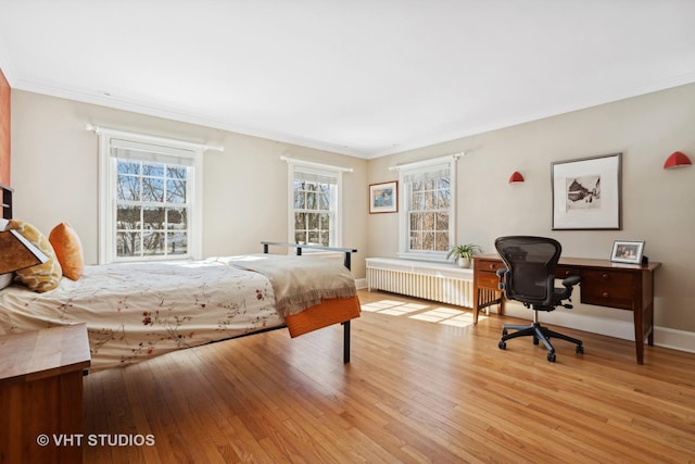 bedroom featuring light wood finished floors, radiator heating unit, baseboards, and crown molding