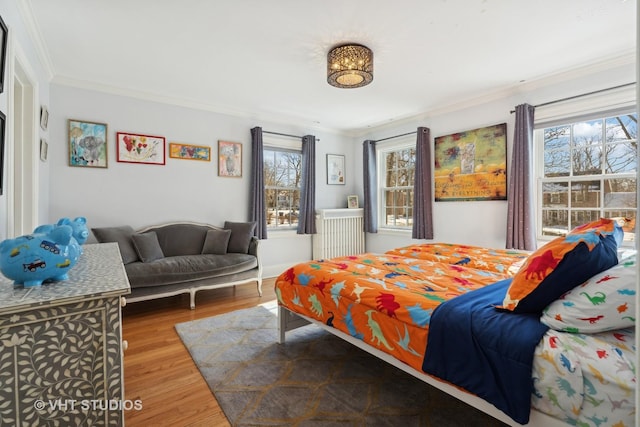 bedroom with ornamental molding, multiple windows, and wood finished floors