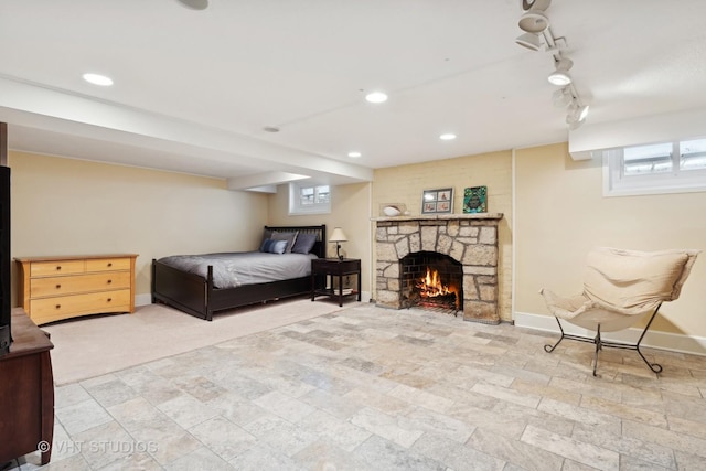 bedroom featuring a stone fireplace, track lighting, recessed lighting, and baseboards