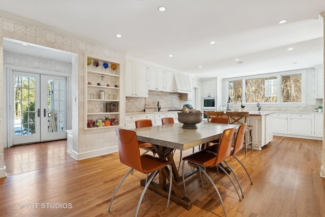 dining space with light wood-style flooring, ornamental molding, and french doors