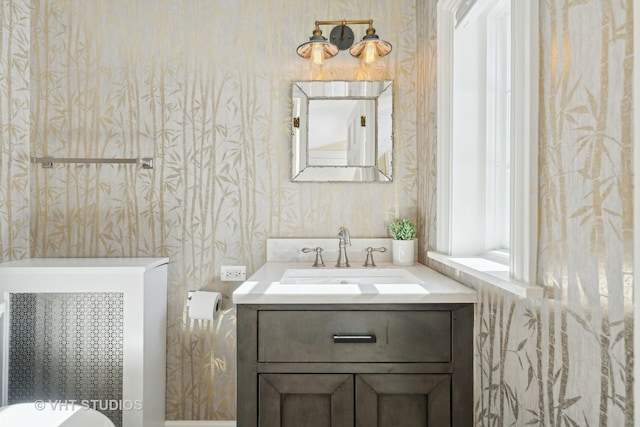 bathroom with wallpapered walls and vanity