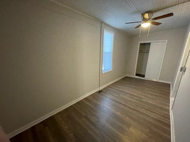 unfurnished bedroom with dark wood-style floors, ceiling fan, baseboards, and a closet