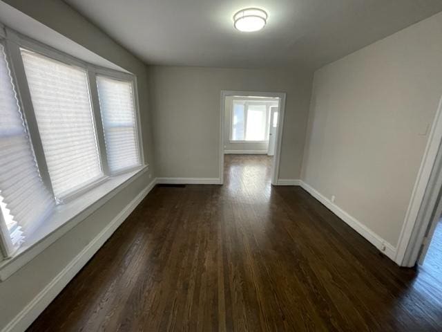 empty room featuring dark wood-style floors and baseboards