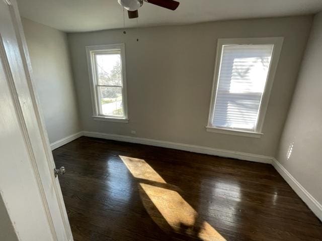 empty room with dark wood-style floors, baseboards, and a ceiling fan