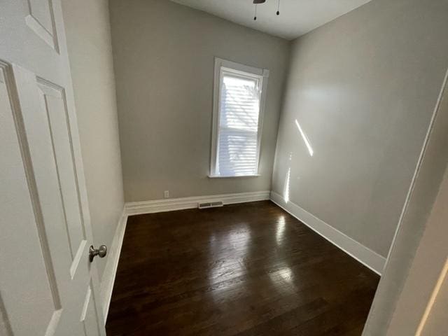 spare room featuring dark wood-style floors, ceiling fan, visible vents, and baseboards